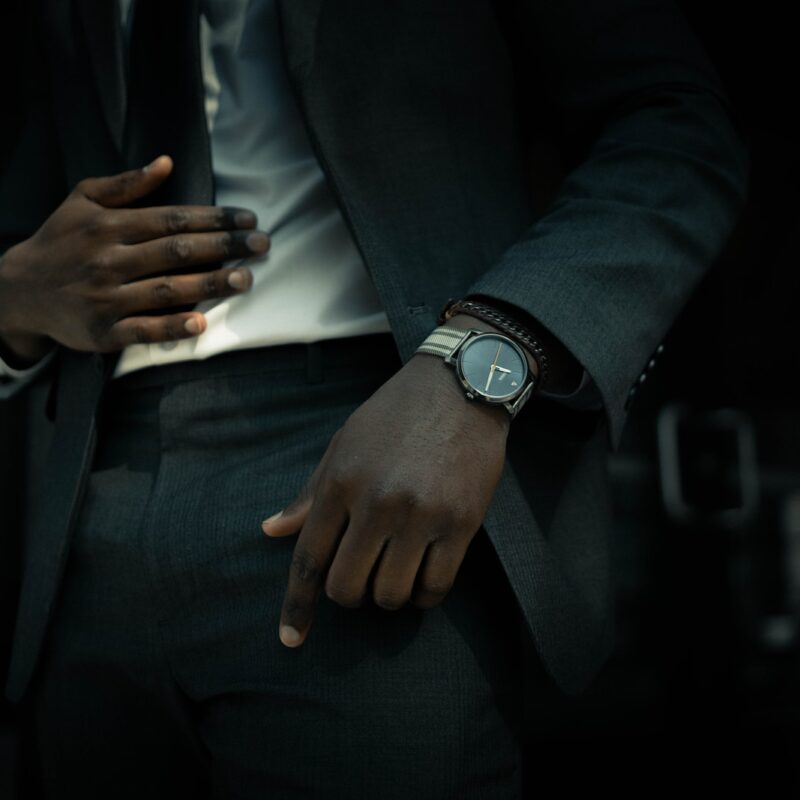 man in black suit jacket and black pants wearing silver round analog watch